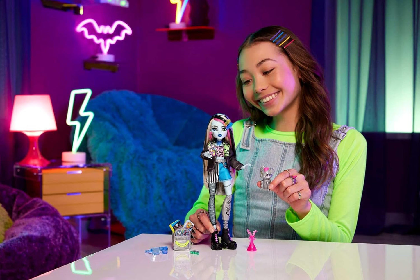 Die Monster High Frankie Stein-Puppe in Jeansjacke und Shorts enthält außerdem ihren Welpen Watzie und Accessoires wie einen Rucksack, einen Snack und ein Notizbuch, HXH73